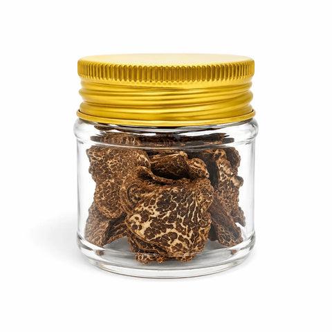 Dried Tuber borchii spring truffle slices in a clear glass jar with a gold lid